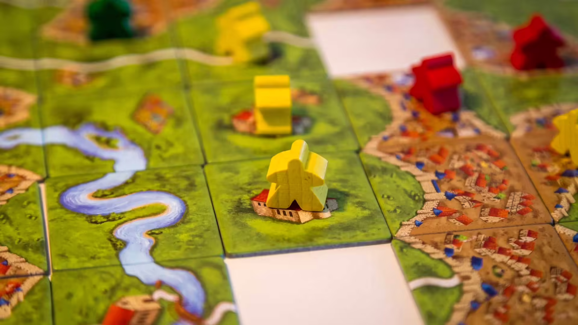 Žltá figúrka meeple na dieliku doskovej hry Carcassonne