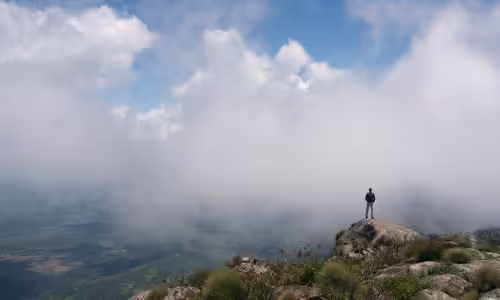 Expedičný lekár Roland Van De Ven na skalnom vrchole Mount Mabu nad oblakmi