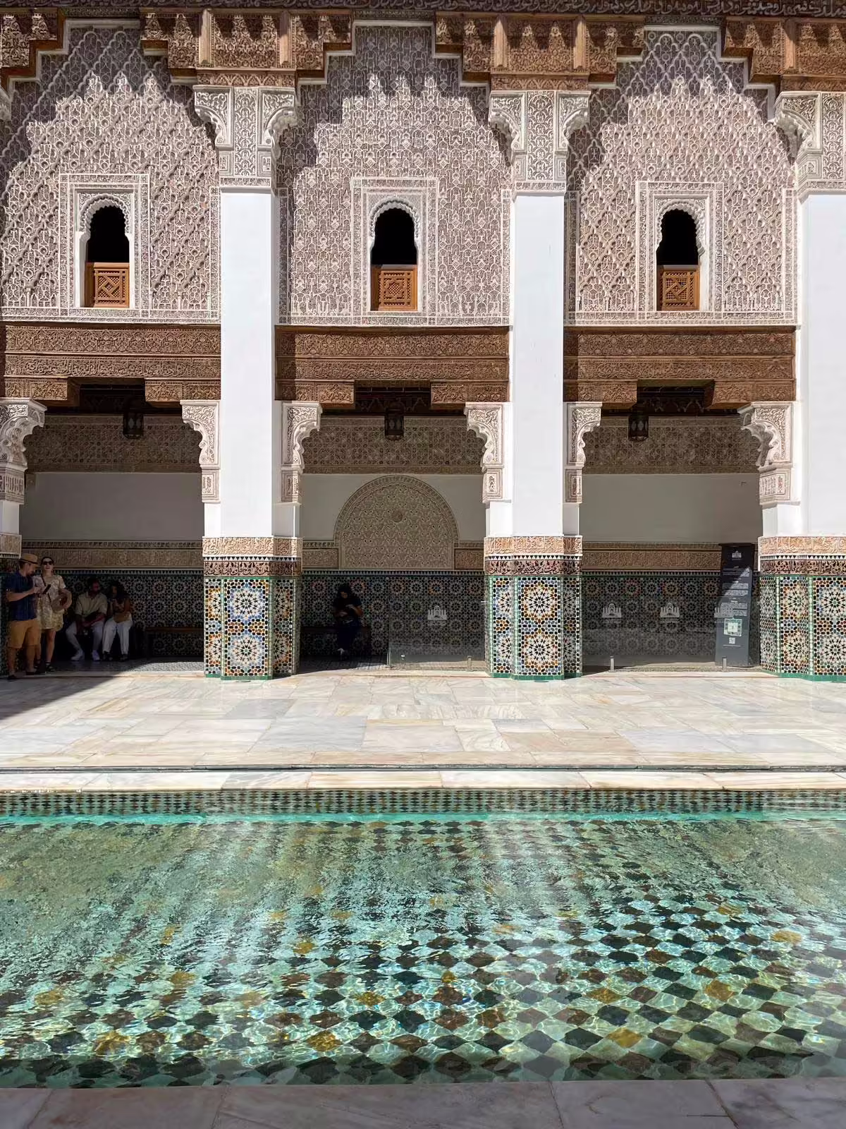 Medresa Ben Youssef – zellige a štuková výzdoba Detail nádvoria medresy Ben Youssef so zellige mozaikami, štukovou výzdobou a oknami na poschodí