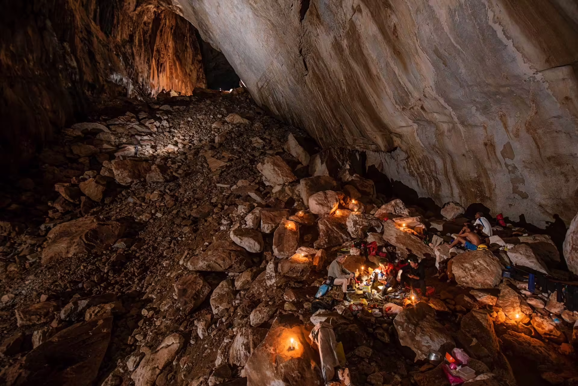 Jaskyniari skúmajú rozsiahlu tmavú jaskyňu s mokrými stenami v národnom parku Gunung Mulu