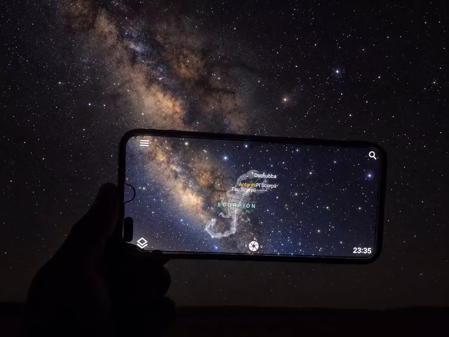 Mobil s astronomickou aplikáciou zobrazujúcou Škorpióna a Antares pred Mliečnou cestou nad Erg Chigaga