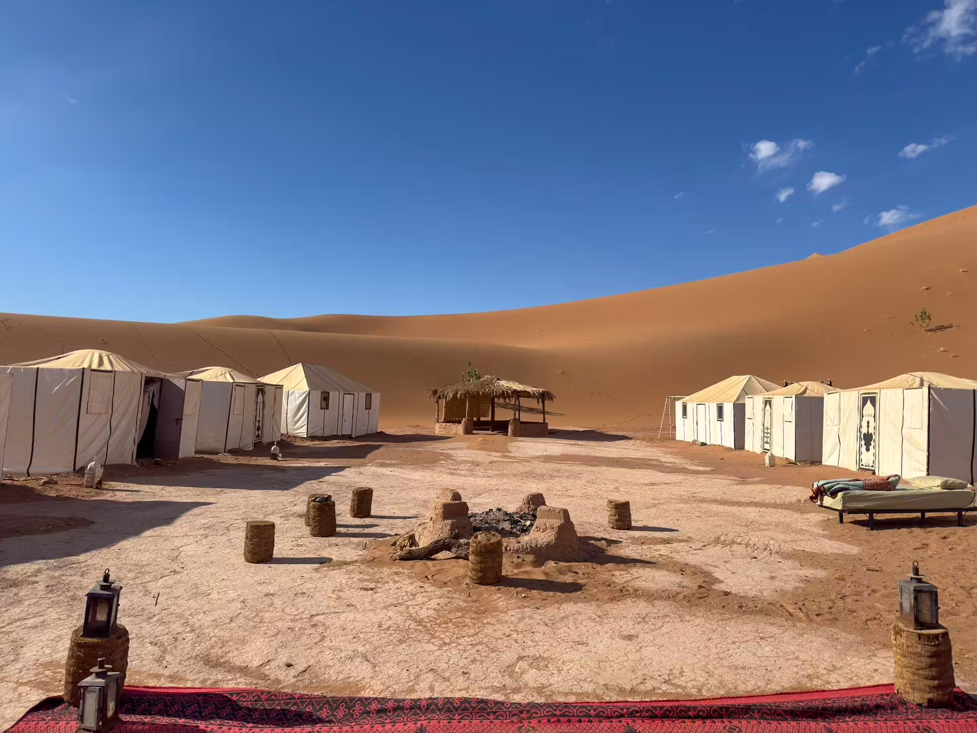 Biely stanový kemp pod vysokými pieskovými dunami Erg Chigaga v marockej Sahare