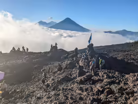 Lávové pole na sopke Pacaya v Guatemale s turistami a výhľadom na okolité vulkány