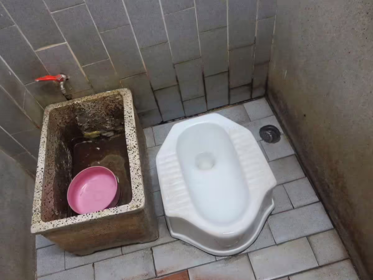 Squat toaleta v Thajsku s nádržou na vodu a miskou na ručné splachovanie