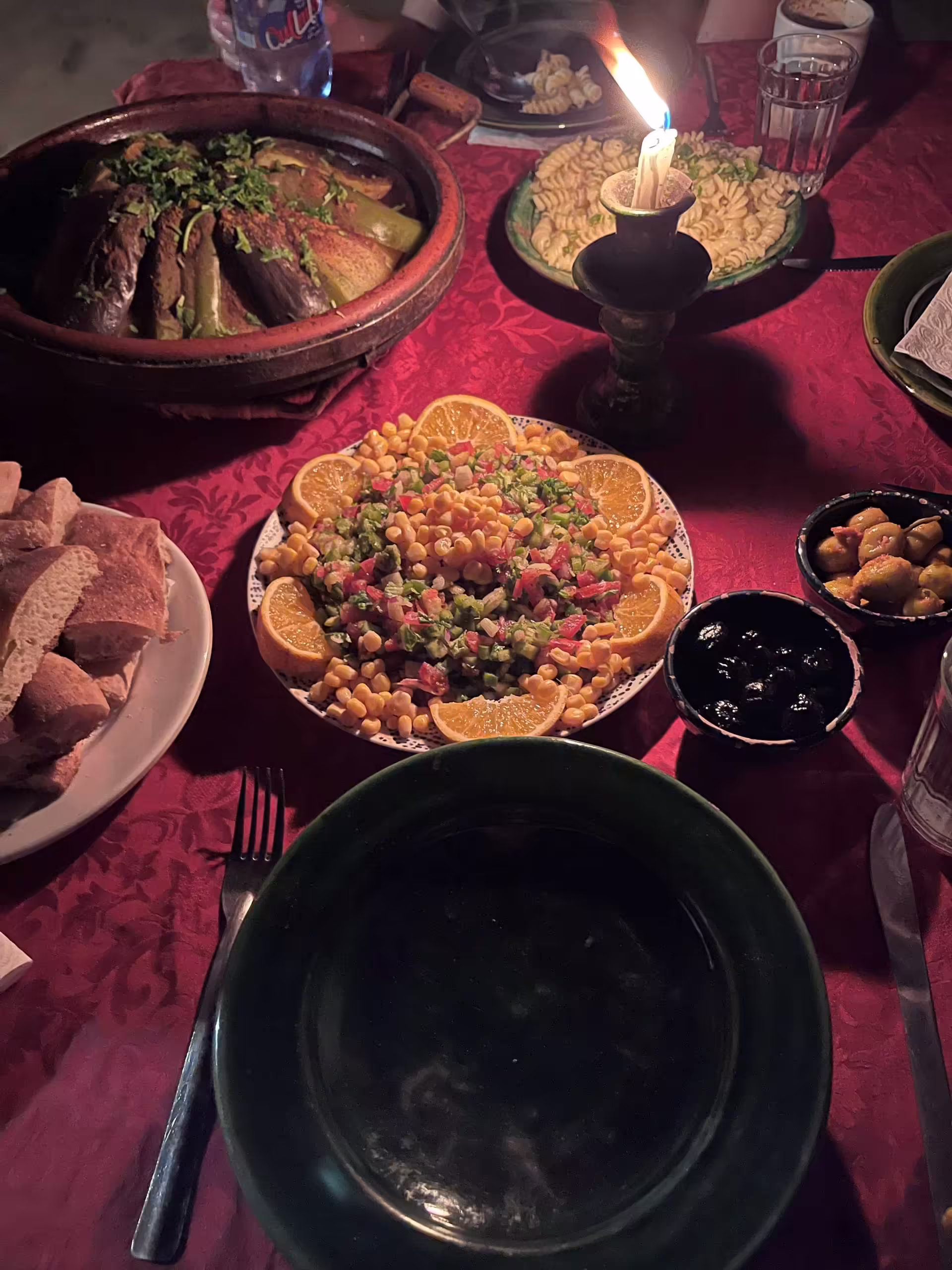 Večera pri sviečke v saharskom kempe s tajine, šalátom, chlebom, olivami a cestovinami