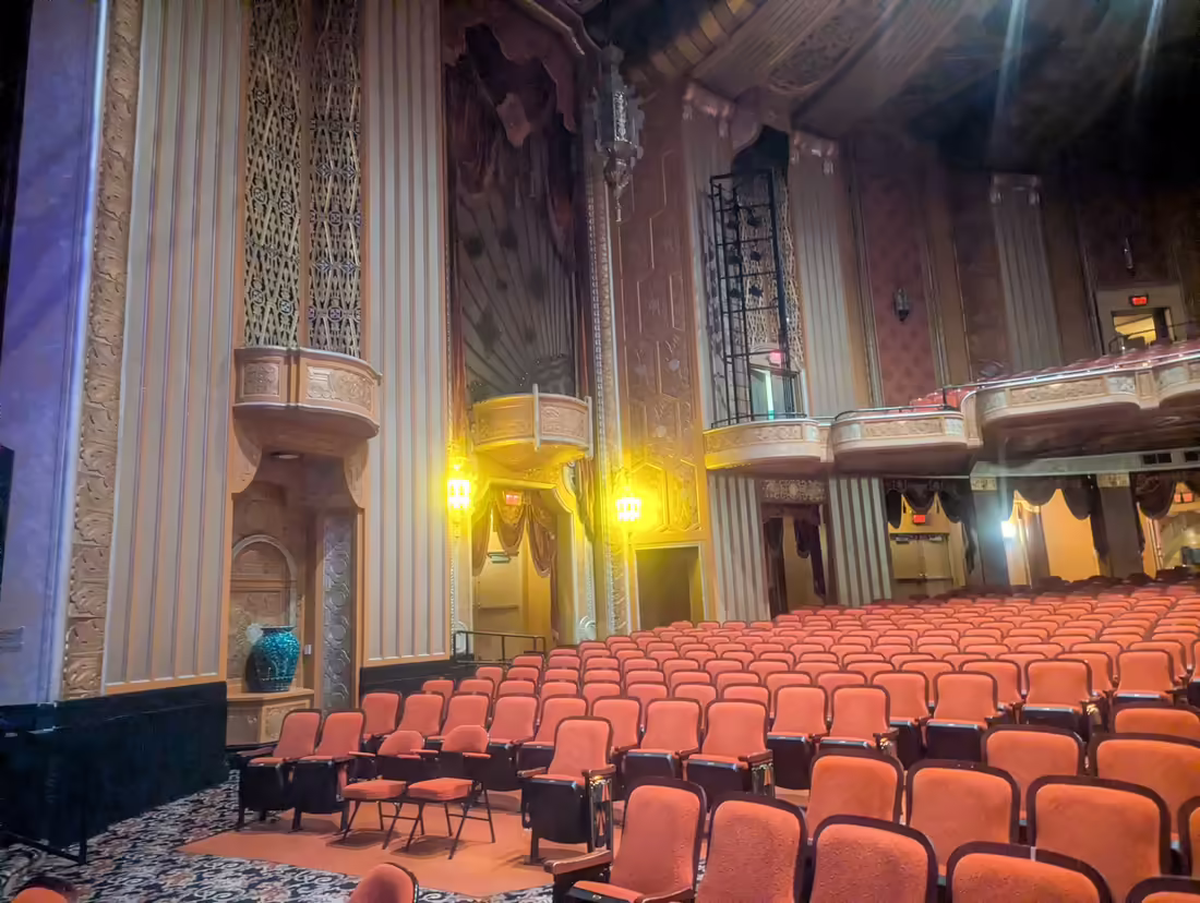 Hľadisko Warner Theatre v Erie s radmi červených sedadiel, balkónmi a dekoratívnymi stenami
