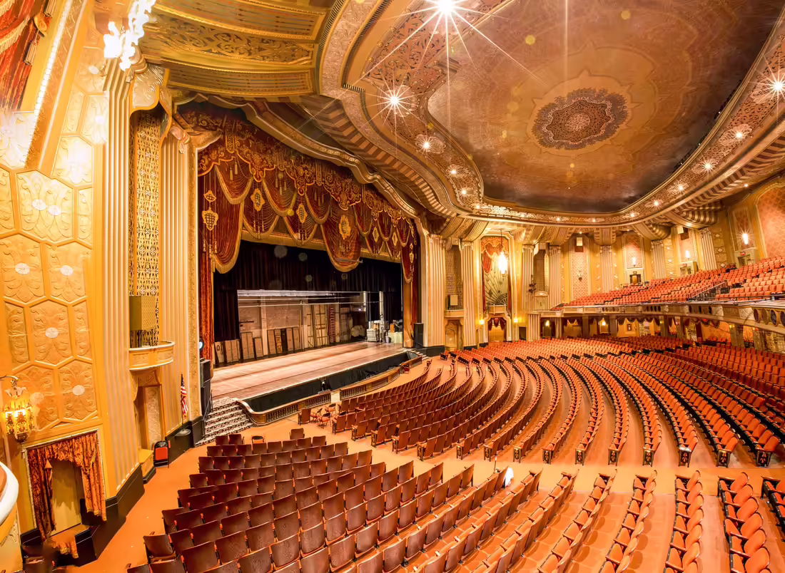 Veľké hľadisko Warner Theatre v Erie s javiskom, balkónom a bohato zdobeným stropom