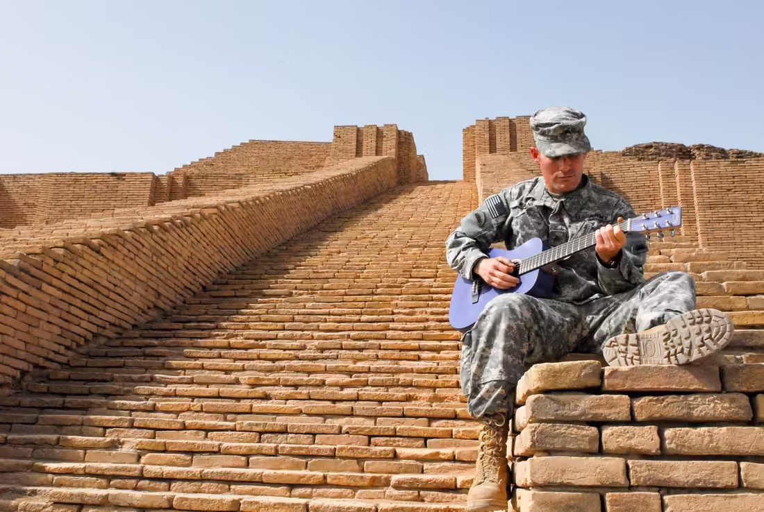 Americký vojak hrá na gitare na schodoch zikkuratu v Ure
