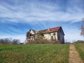 Chátrajúci drevený dom s hrdzavou plechovou strechou v Henry River Mill Village