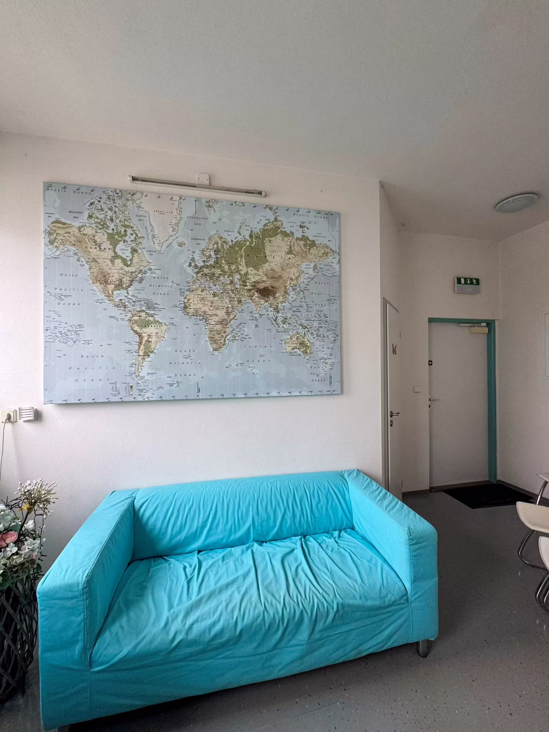Veľká mapa sveta na stene nad tyrkysovou sedačkou v čakárni INOCEM v Bratislave.
