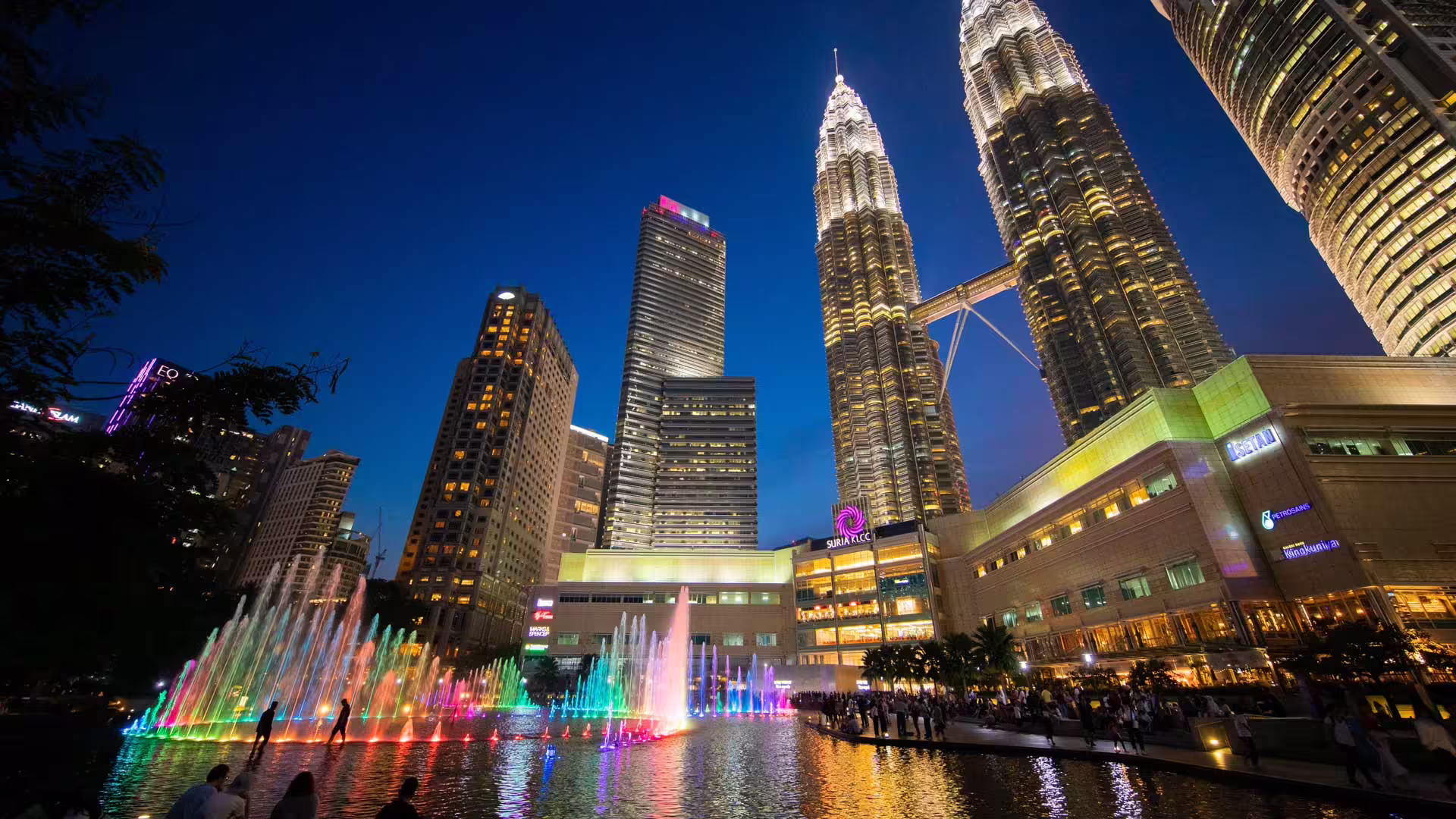 Večer osvetlené Petronas Twin Towers a farebné fontány pri KLCC v Kuala Lumpur v Malajzii