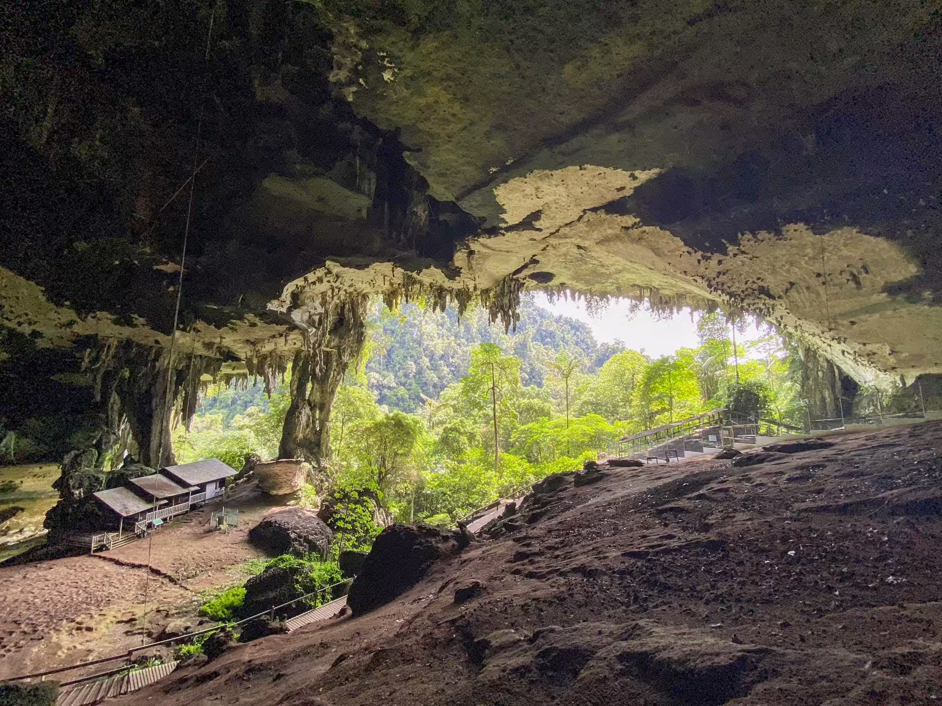 Mohutný vstup do jaskýň Niah s dreveným chodníkom a tropickou vegetáciou v pozadí