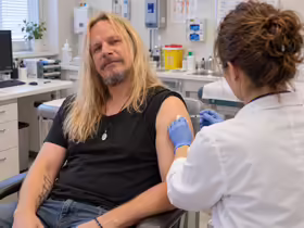 Cestovateľ pri očkovaní do ramena v ambulancii INOCEM v Bratislave, zdravotníčka má modré rukavice.