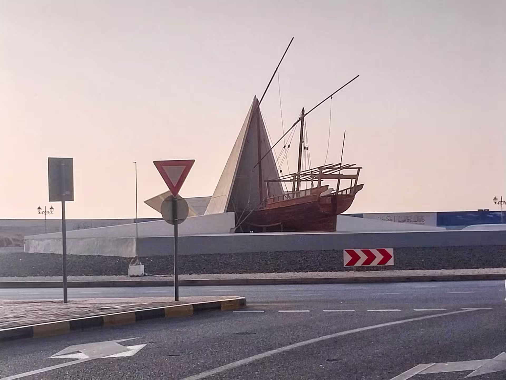 Drevená loď Al-Barraqah vystupujúca z bielej papierovej lode na kruhovom objazde pri Ajman Corniche