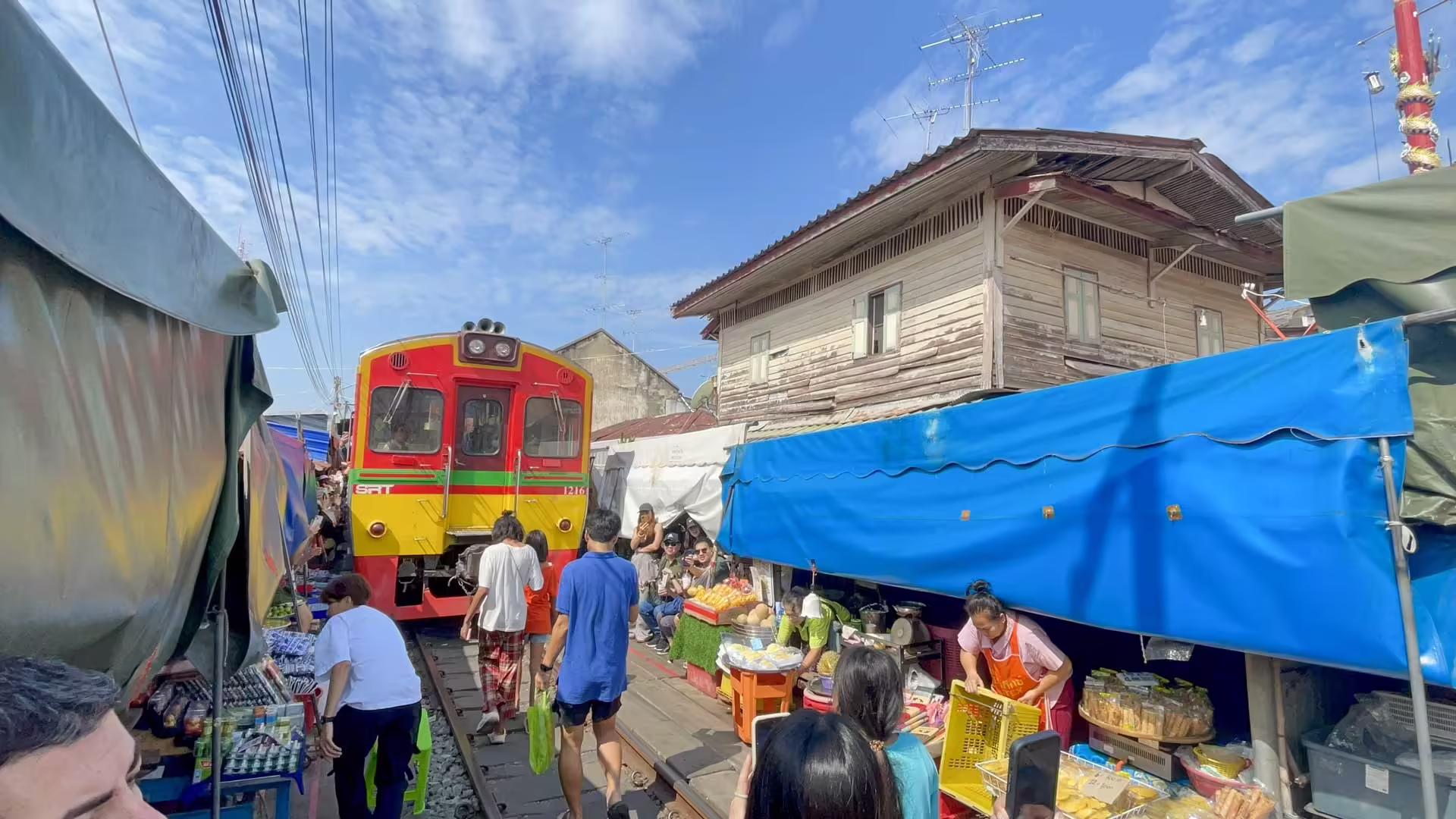 Vlak SRT prechádza pomedzi stánky na železničnom trhu Maeklong v Thajsku